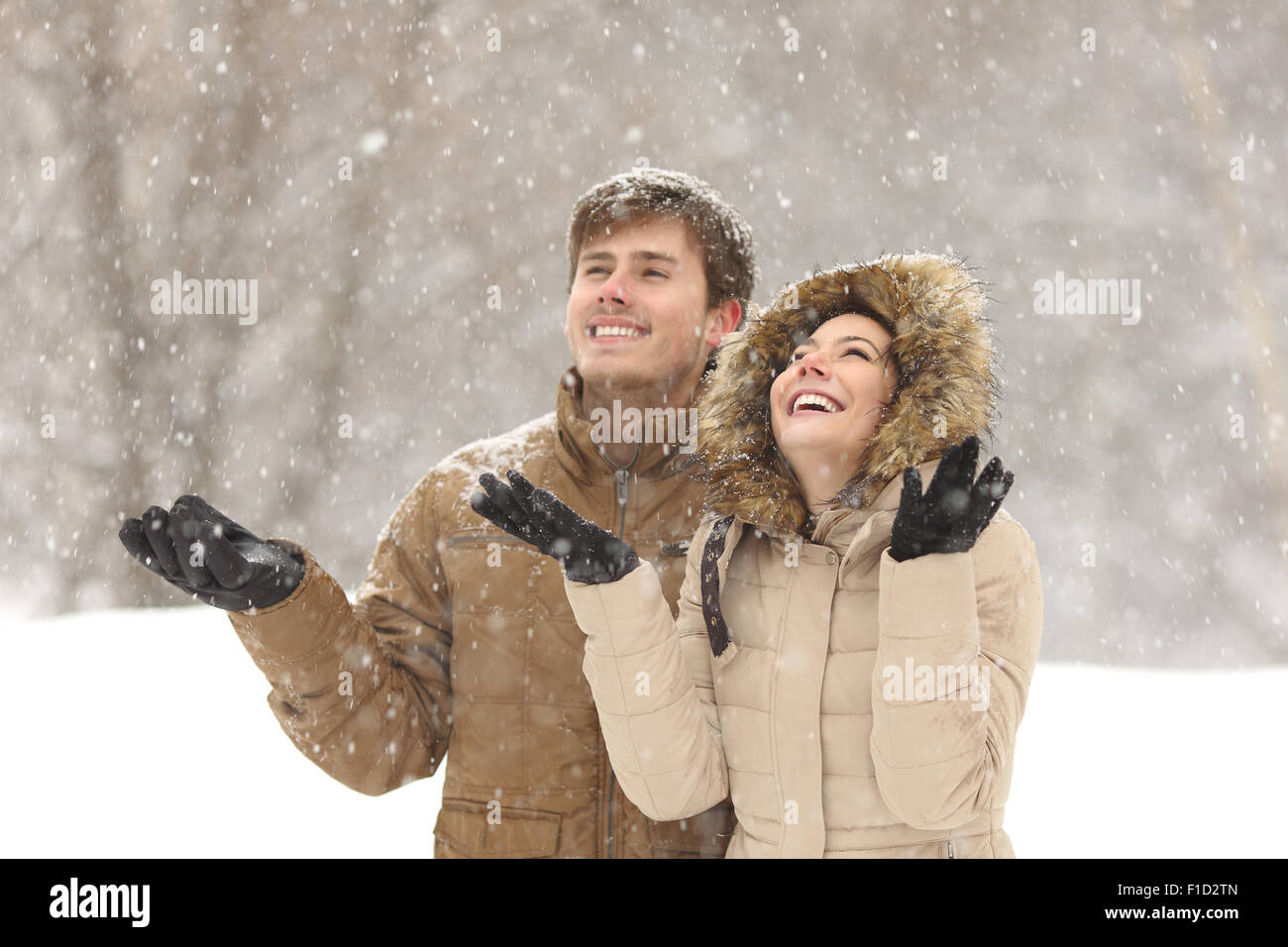 Lustige paar beobachten Schnee im Winter bei Schneefall an Feiertagen Stockfoto