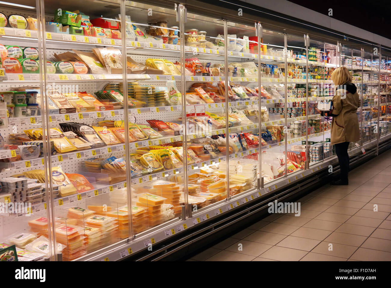 Verkäuferin füllt die Regale in den gekühlten Frischprodukten Gang eines Delhaize Supermarkt. Stockfoto