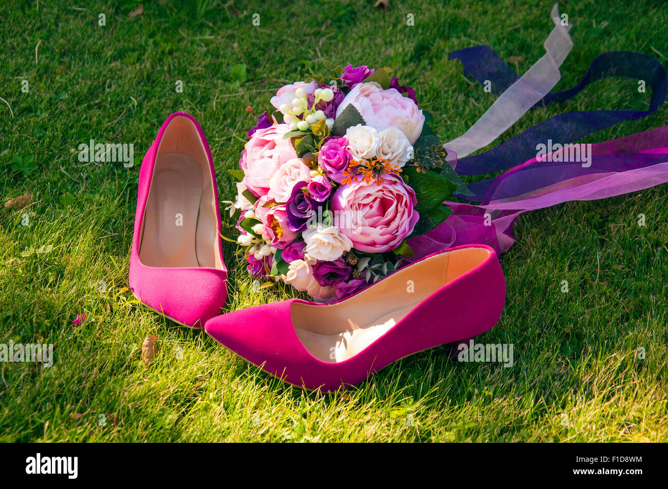 Ein Brautstrauß mit rosa Schuhen der Braut auf dem Rasen Stockfoto