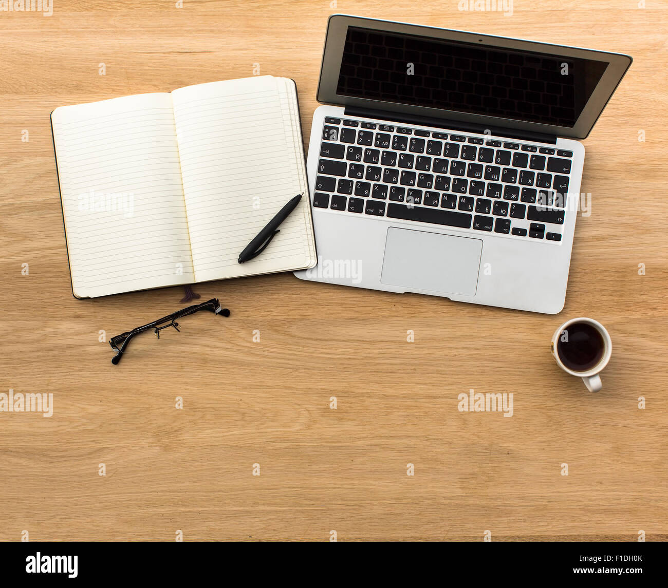 Laptop, offene Notizblock, Stift, Gläser und Tasse Kaffee auf dem Tisch, hellem Holz. Draufsicht mit Platz für Ihren Text. Stockfoto
