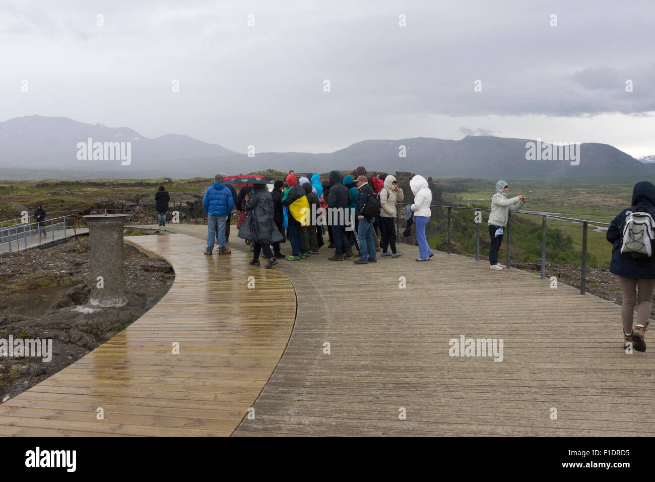 Im Pingvellir National Park, Island, tummeln sich die Touristen im Regen mit einem grauen, bewölkten Himmel, der im August schlechtes Wetter signalisiert Stockfoto