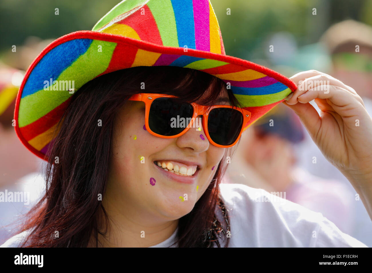 Frau eine Nächstenliebe Farbe ausgeführt, trägt einen bunten Stetson Hut  und Kunststoff Sonnenbrillen, Kilwinning, Schottland Stockfotografie - Alamy