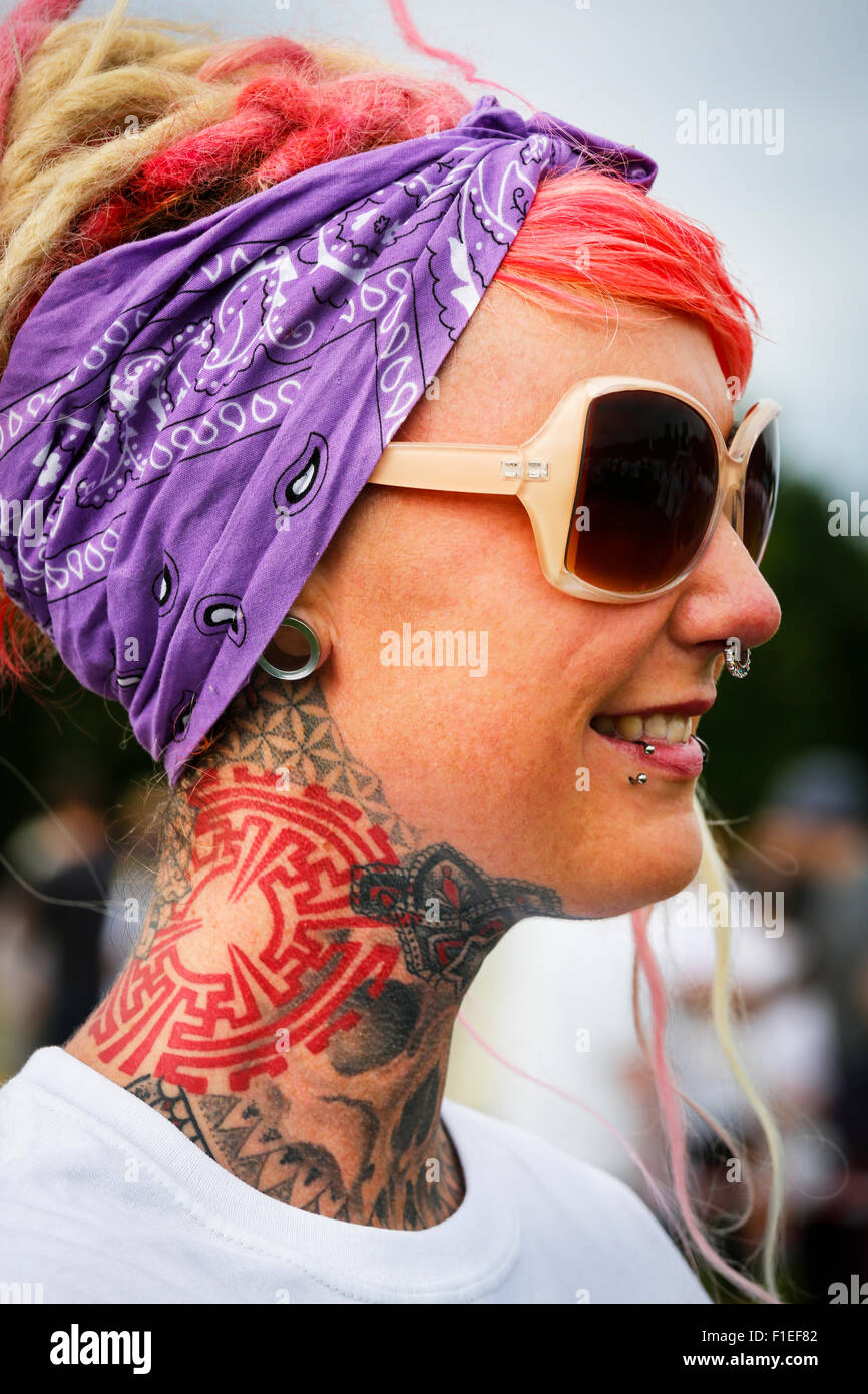 Junge Frau posiert, um fotografiert zu werden, um ihren Hals Tattoo und Gesichtsbehandlung Nieten und Piercings zu zeigen. Stockfoto