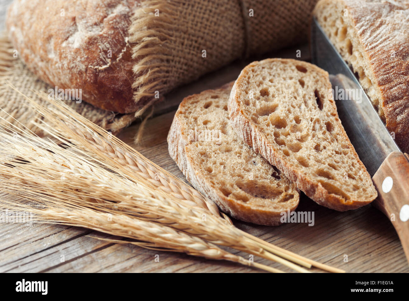 Frisches Brot in Scheiben schneiden und Roggen Ohren auf rustikalen Tisch. Stockfoto