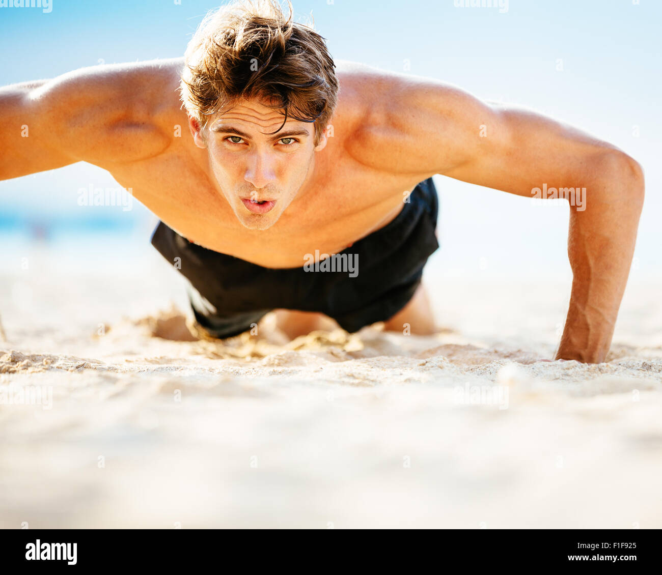 Passen Sie jungen Mann Liegestütze am Strand zu tun. Training im freien Strand. Hübscher Junge Fitness Mann ausüben. Sport und einen aktiven Lebensstil Stockfoto