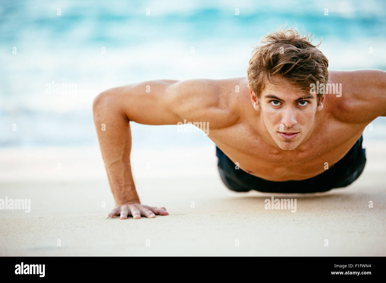 Fitness Mann tut Liegestütze am Strand. Sportler, die Bewegung in der Natur. Sport und einen aktiven Lebensstil. Stockfoto