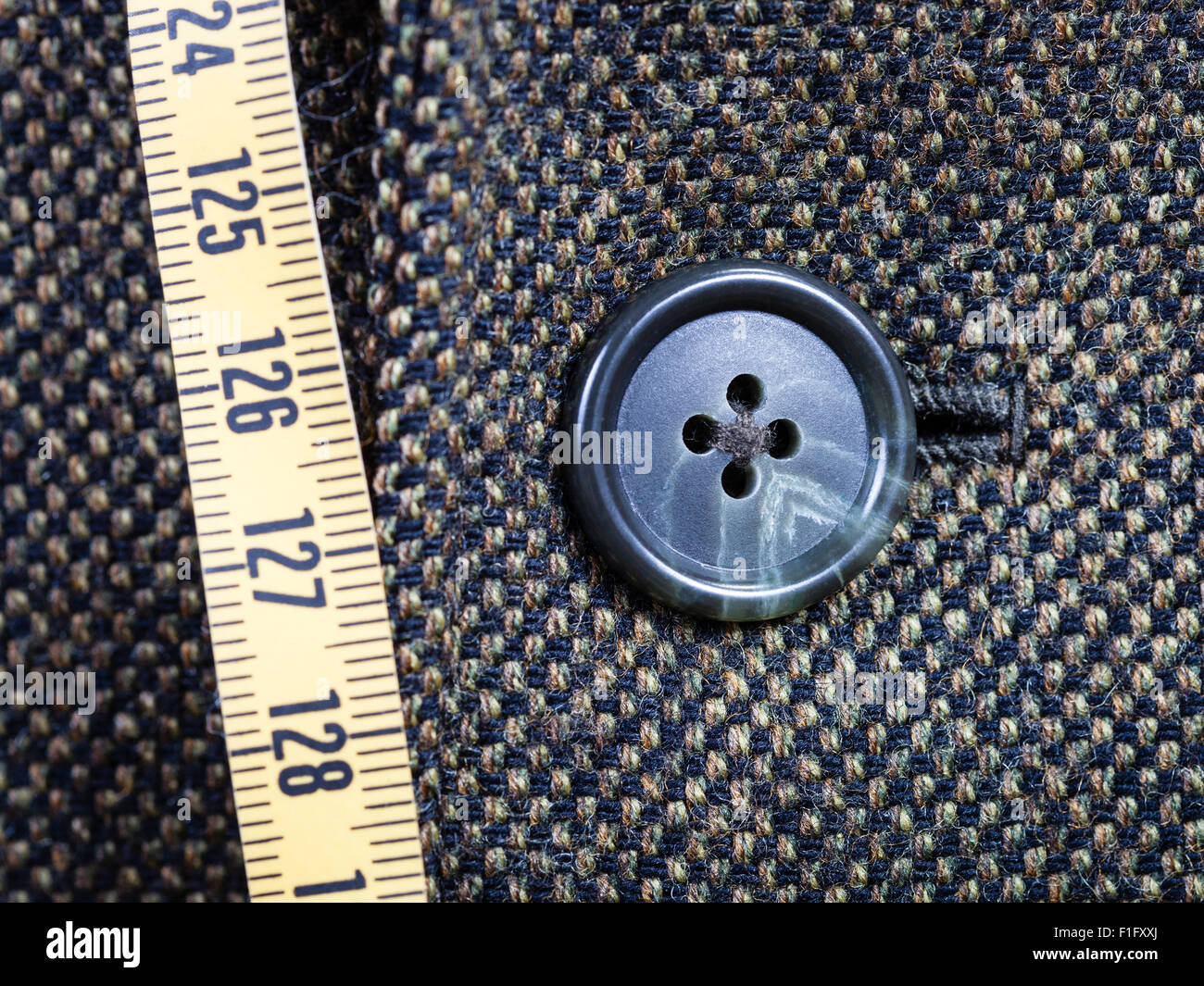 Schneider, die Messung von Band und geknöpfte Taste auf Tweed-Jacke hautnah Stockfoto