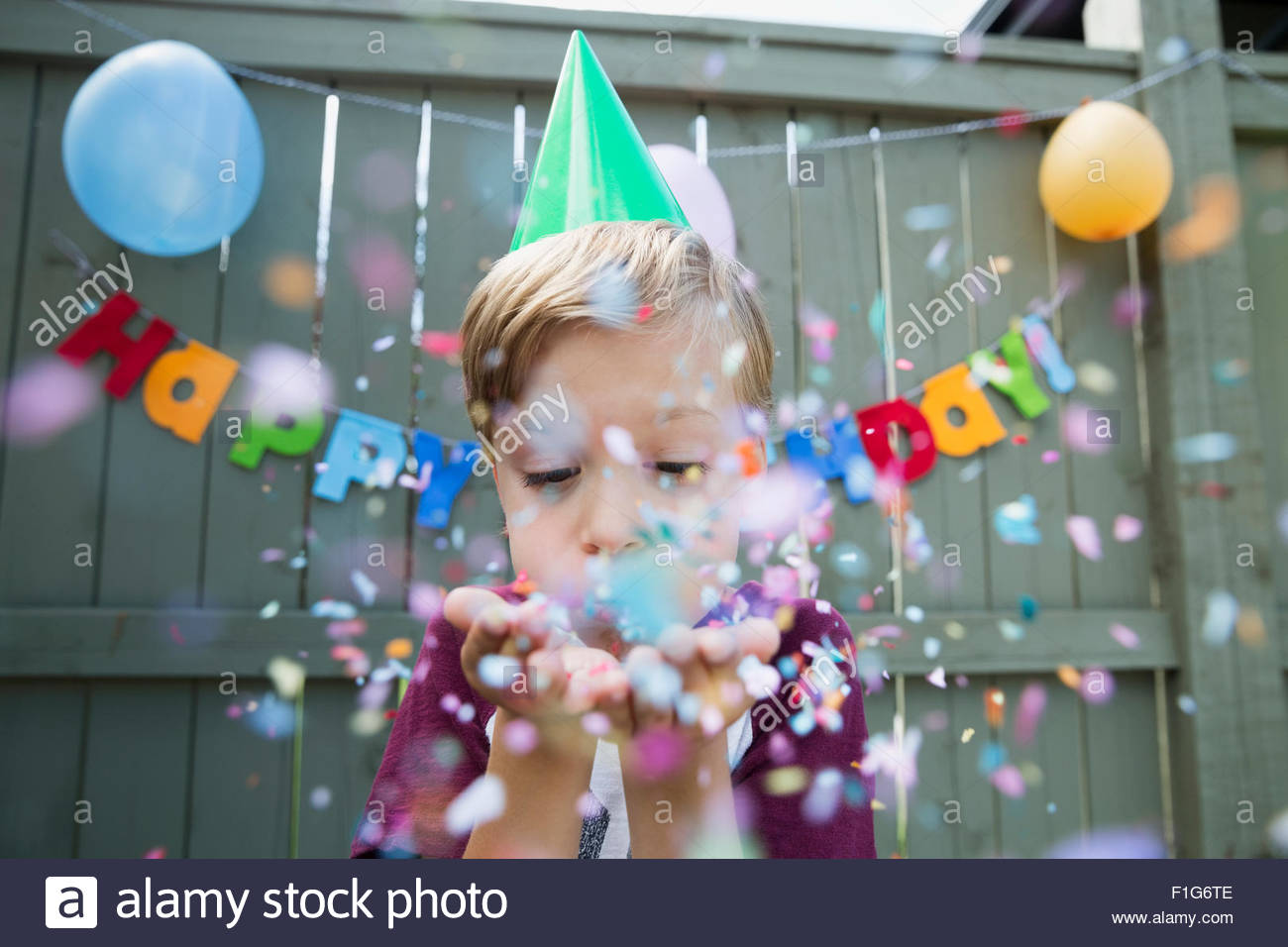 Boy bläst Konfetti Geburtstag Party Hut Stockfoto