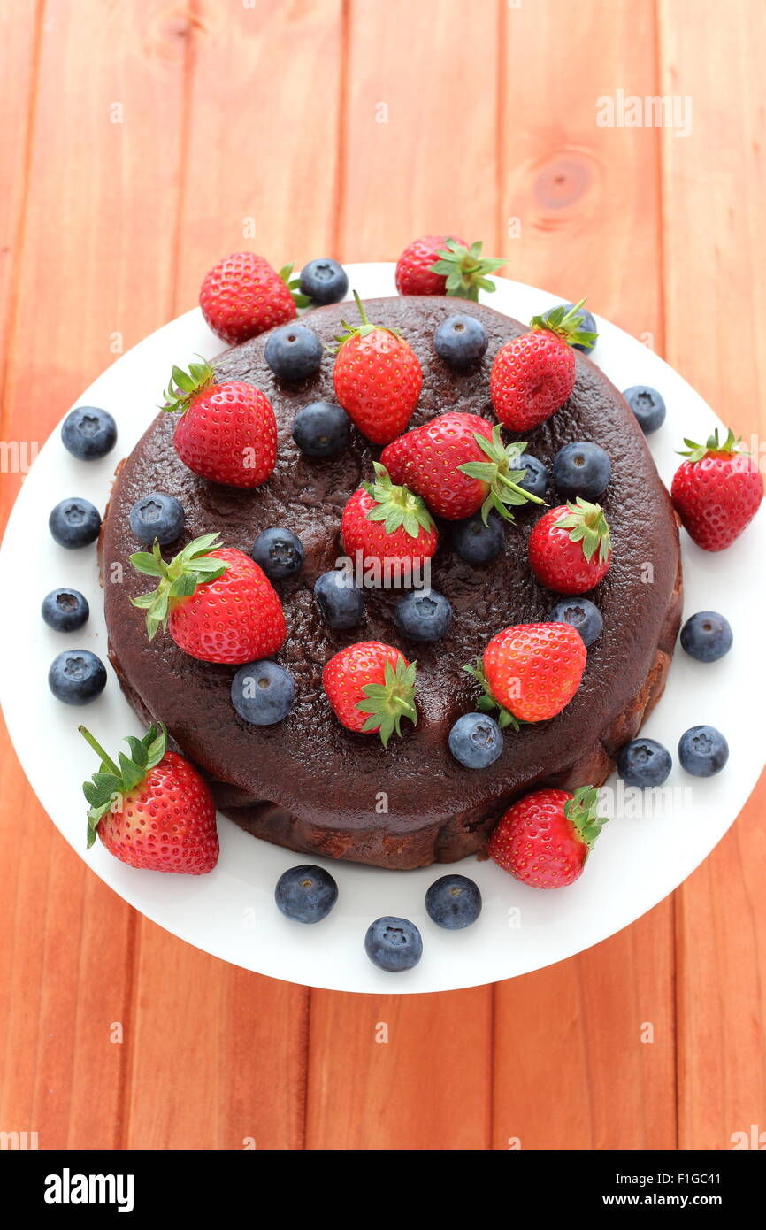 Nahaufnahme von Schokoladenkuchen mit Beeren an der Spitze aus Holz Hintergrund Stockfoto