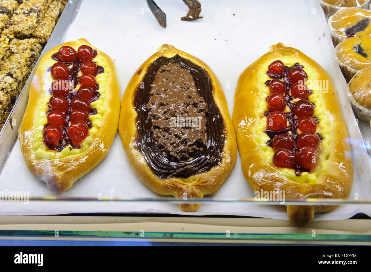 Gelber Kuchen mit Kirschen und Chociolate zum Verkauf in einer Bäckerei in Fira, Santorini, Griechenland. Stockfoto