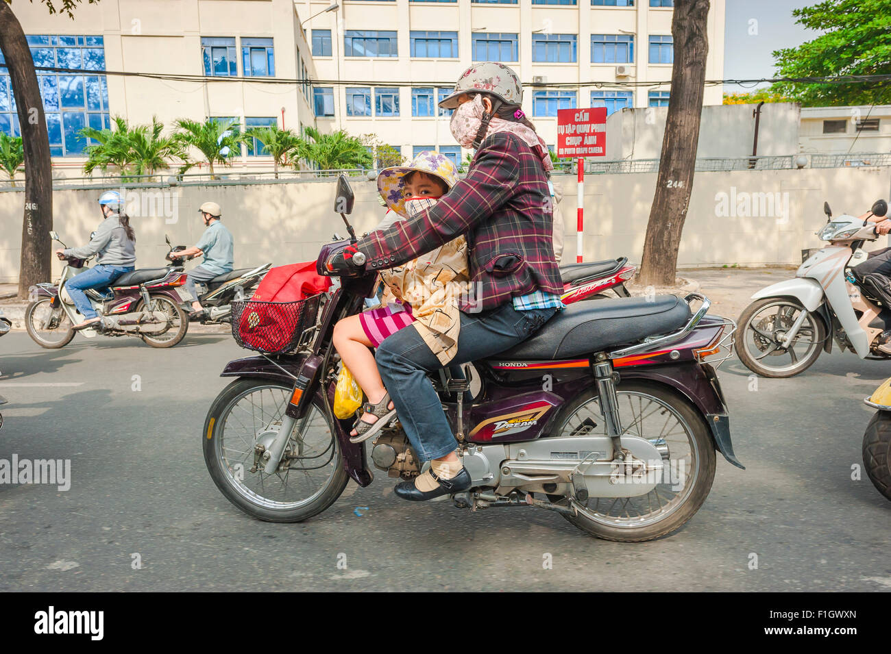 Mutter Kind Motorrad, eine Frau und ihre Tochter fahren mit dem Motorrad im Berufsverkehr entlang Tran Hung Dao in Ho Chi Minh City, HO CHI MINH CITY, Vietnam. Stockfoto