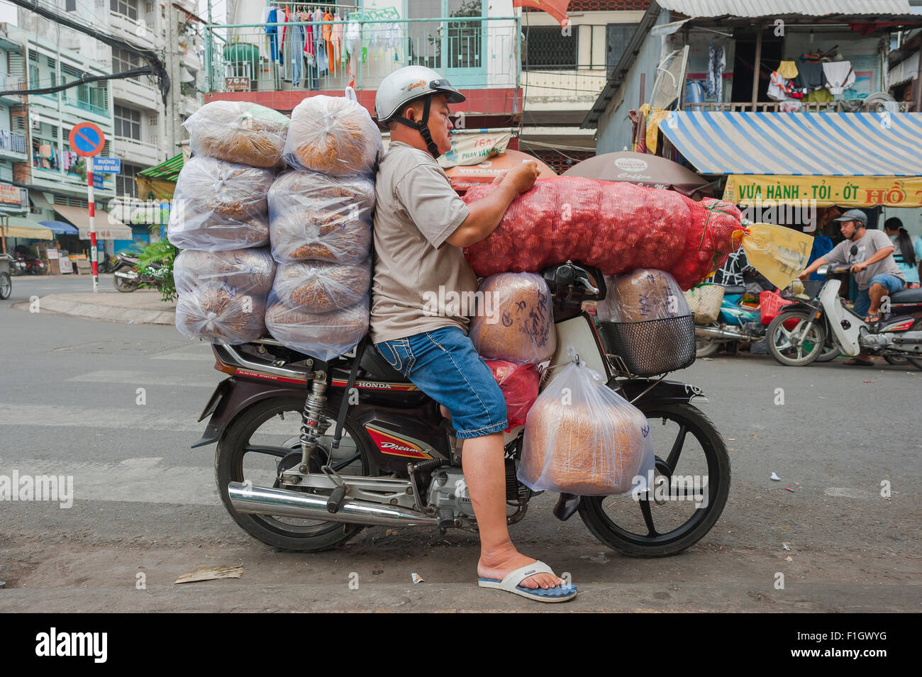 Überlastet Motorrad Vietnam, ein Motorrad porter Pausen ständig überlastet sein Fahrzeug in eine Straße in der Binh Tay Bereich Cholon, Saigon, Vietnam Stockfoto