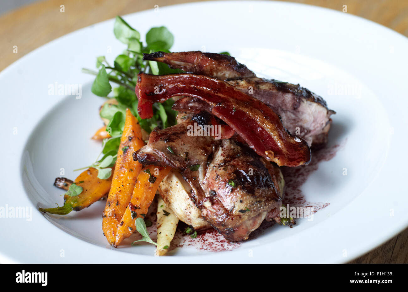 Ein Gourmet-Rindfleisch-Gelenk mit Speck, Orangenschale, Pastinaken und Salat serviert. Stockfoto