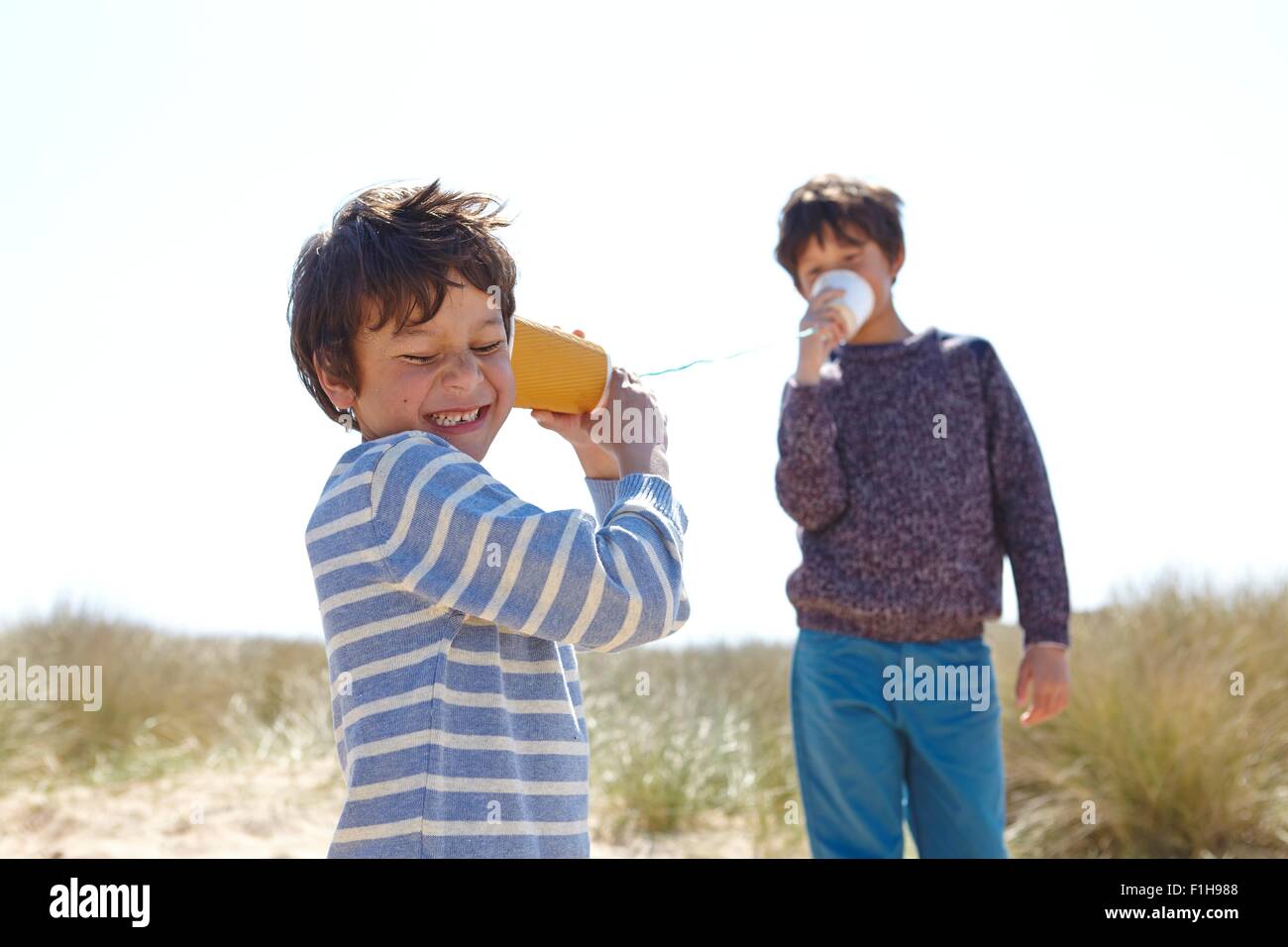Zwei Jungen spielen mit Cup und Zeichenfolge Telefon Stockfoto
