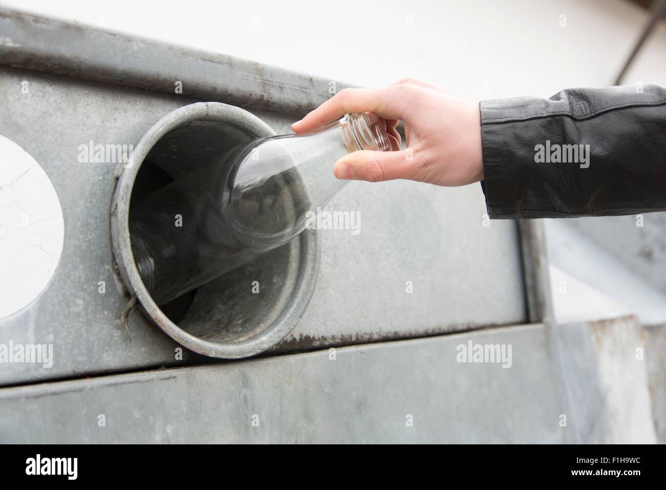 Person recycling Milchflasche in Altglascontainer Stockfoto