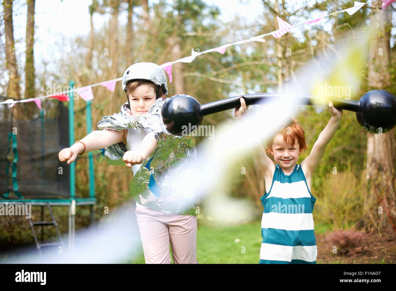 Kleine Kinder tragen Kostüme, spielen im Garten Stockfoto