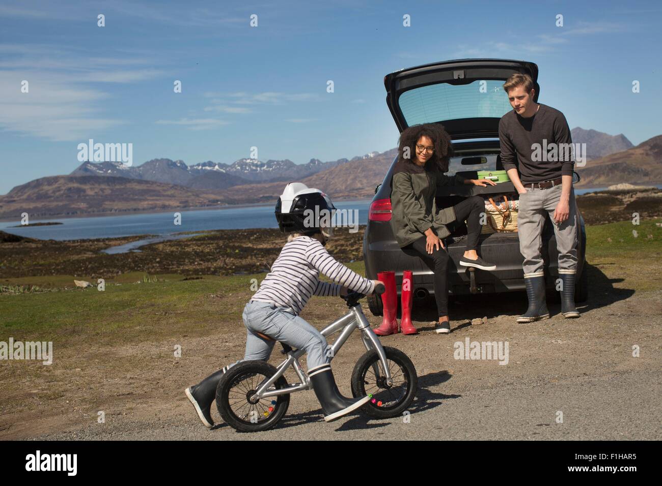 Eltern beobachten Sohn Fahrt Fahrrad, Loch Eishort, Isle Of Skye, Hebriden, Schottland Stockfoto