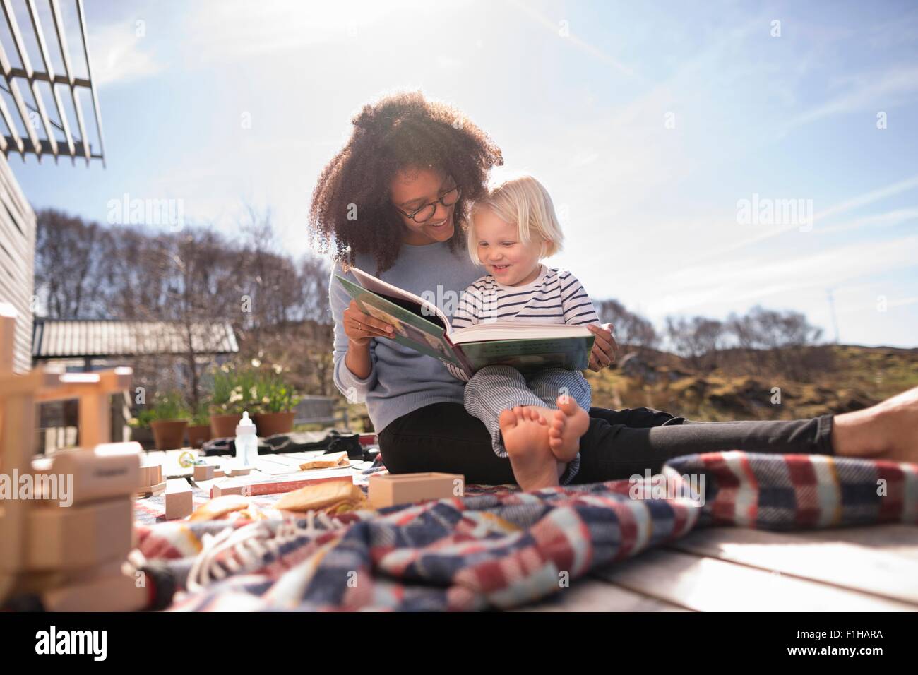 Mutter Lesebuch Sohn auf der Picknickdecke Stockfoto