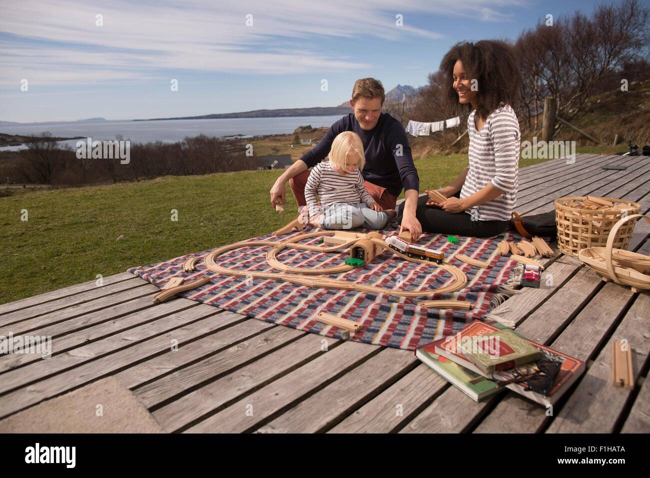 Junge und Eltern spielen mit Spielzeug Zug auf Holzterrassen Stockfoto