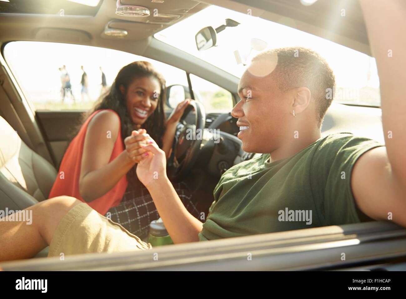 Junges Paar sitzt im Auto, die Hand in Hand Stockfoto