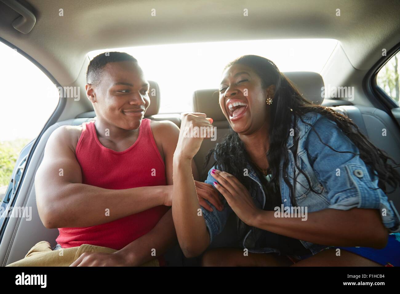 Junges Paar im Auto lachen, Frau Muskeln Stockfoto