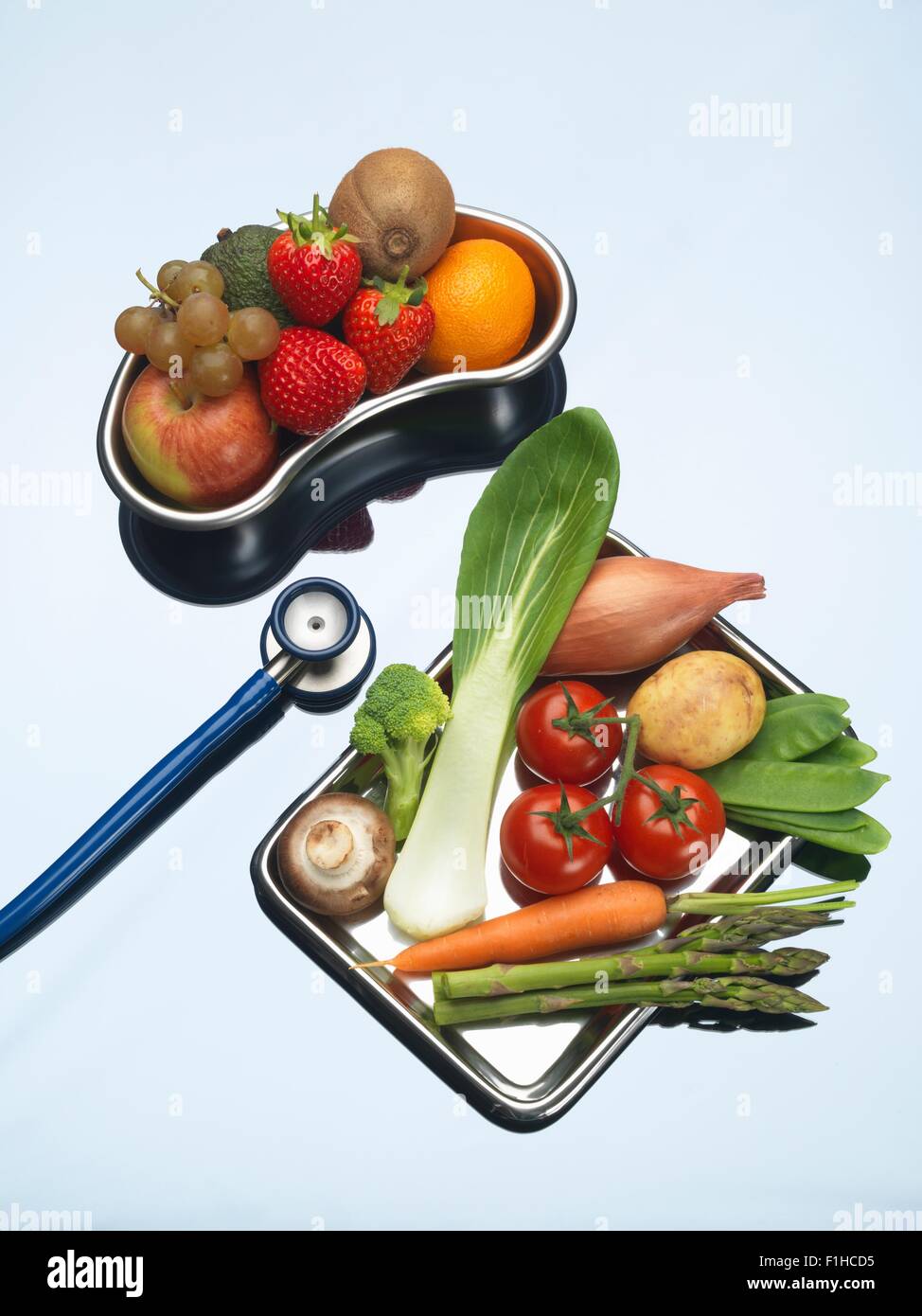 Stethoskop zwischen Schalen mit frischem Obst und Gemüse Stockfoto