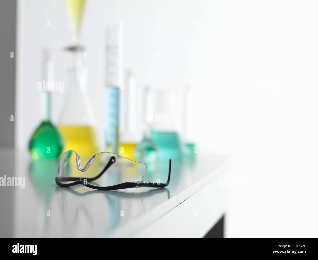 Schutzbrille auf Labortisch mit einem chemischen Experiment im Hintergrund Stockfoto
