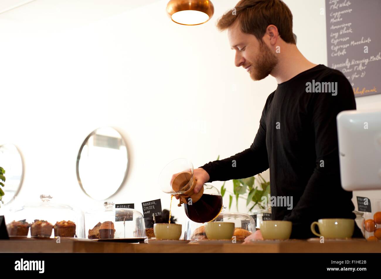 Cafe Kellner gießt frischem Filterkaffee in Tassen Stockfoto