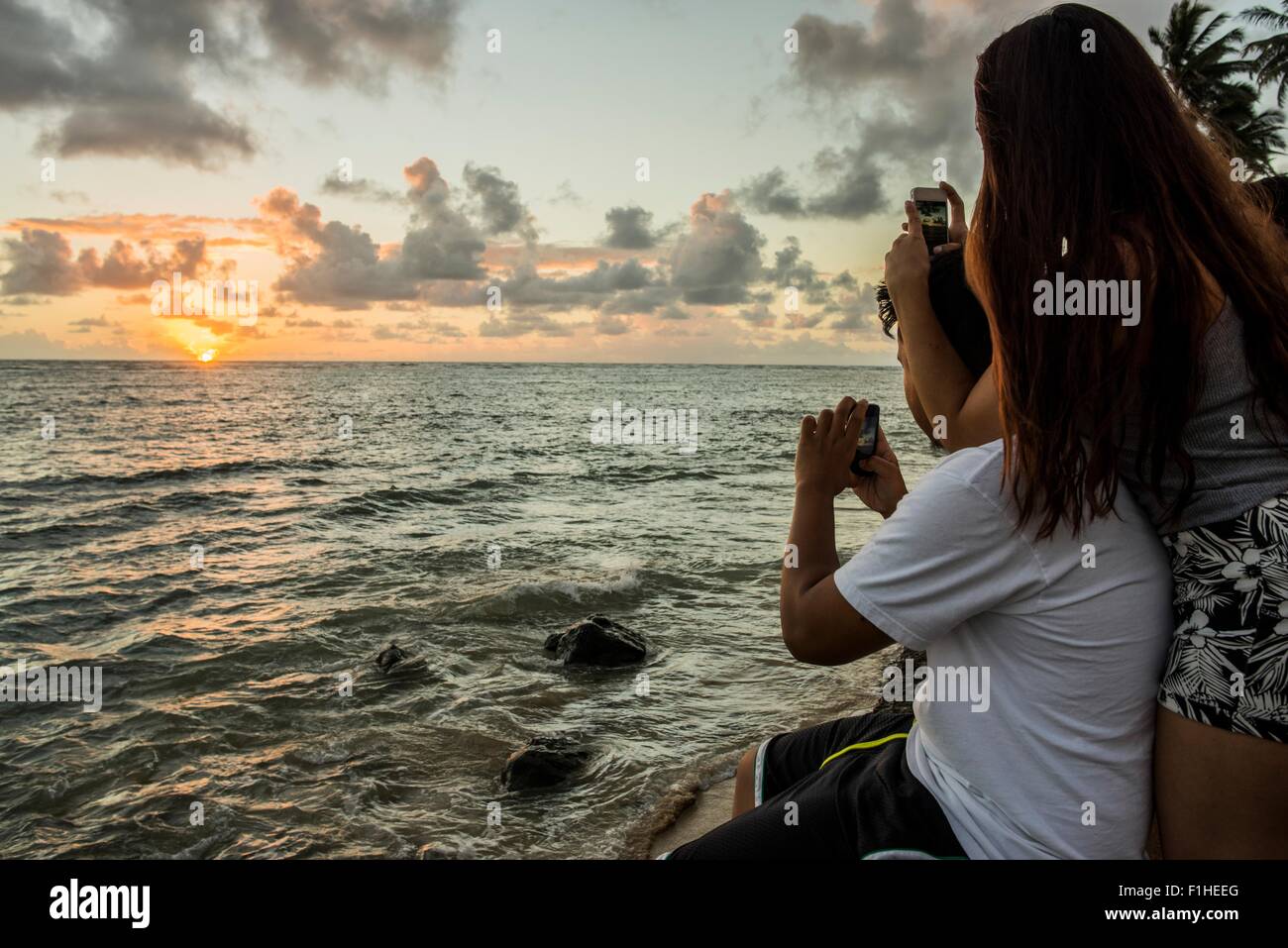 Paar fotografieren Sonnenaufgang auf Smartphones, Kaaawa Strand, Oahu, Hawaii, USA Stockfoto