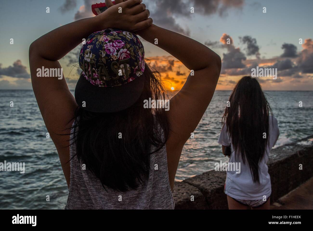 Zwei junge Frauen, die gerade Sonnenaufgang, Kaaawa Strand, Oahu, Hawaii, USA Stockfoto