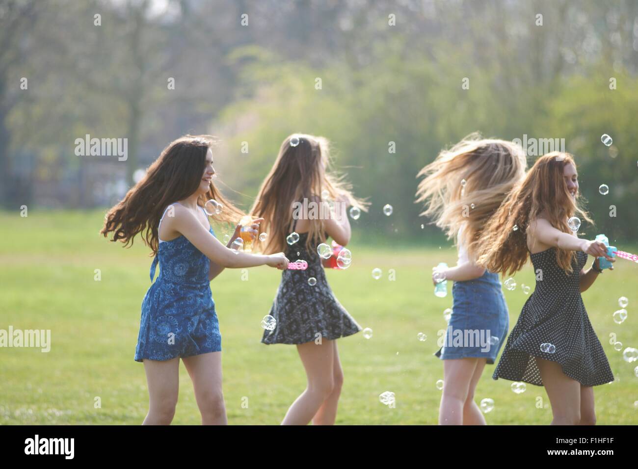 Vier Mädchen im Teenageralter spinning Bubbles mit Blase Wand im park Stockfoto