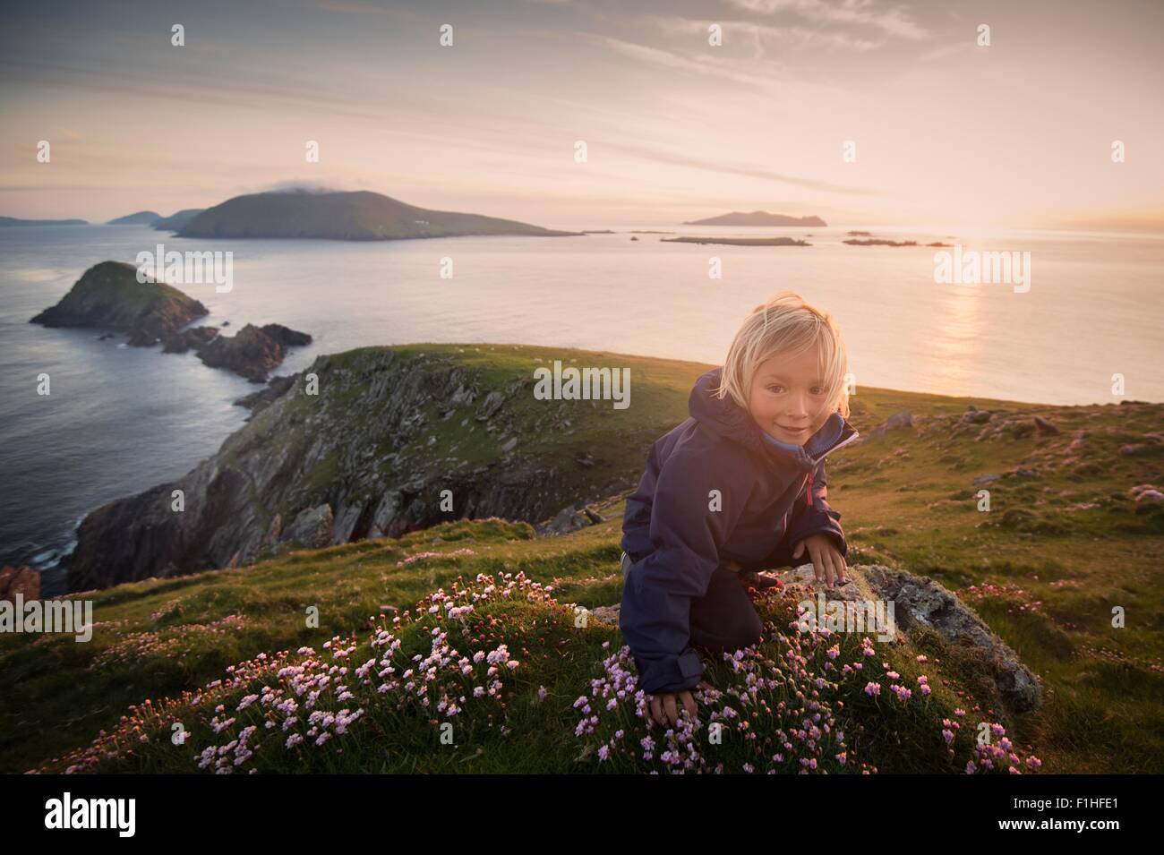 Kleiner Junge sitzt auf Hügel, Slea Head, County Kerry, Irland Stockfoto