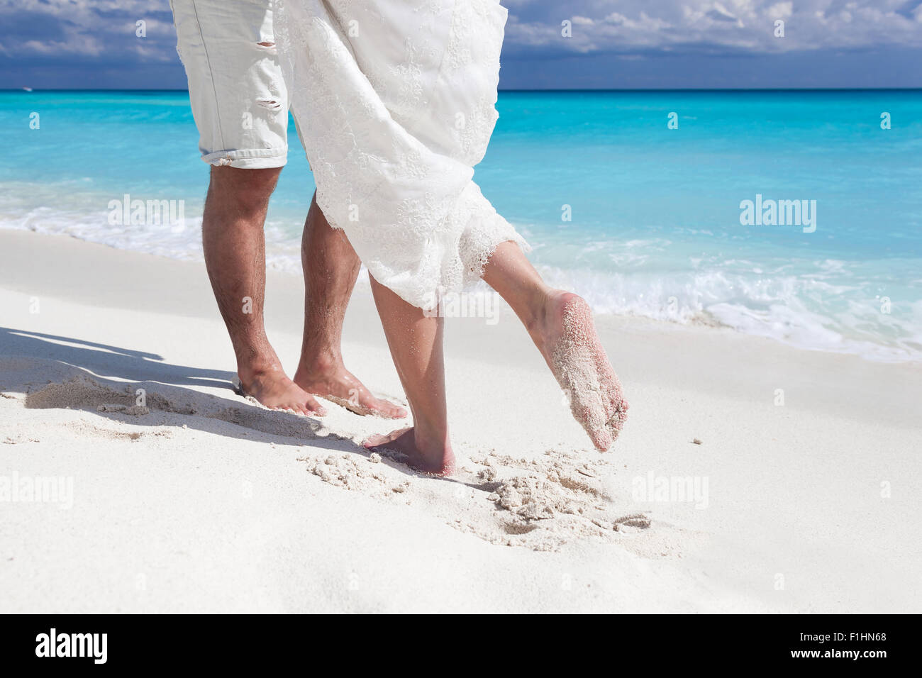 Männliche und weibliche Füße auf weißem Sand, küssen Nahaufnahme Stockfoto