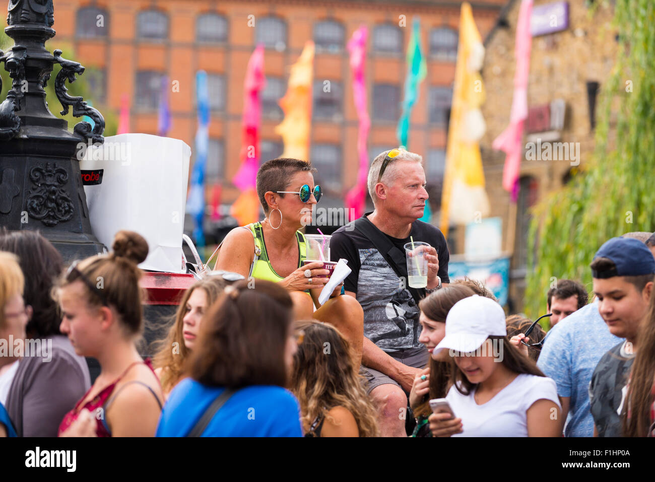 London, Camden Town, Lock Kanalbrücke Touristen alkoholfreie Getränke in der Hand sitzen auf Bridge als Menschenmassen zu Fuß durch die Sommersonne Stockfoto