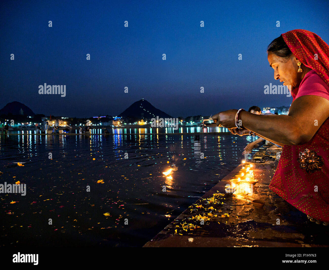 Eine indische Frau mit einem Teller des Feuers gegen Heiligen Pushkar-See am Abend gegen blauen Himmel Stockfoto