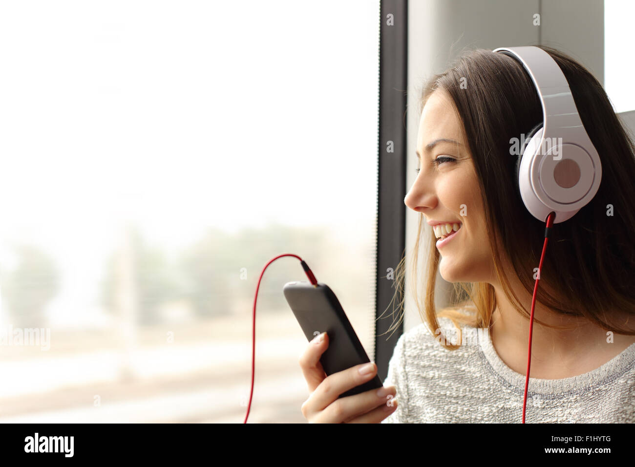 Happy Teen Passagier Musikhören unterwegs im Zug und schauen durch die Fenster Stockfoto