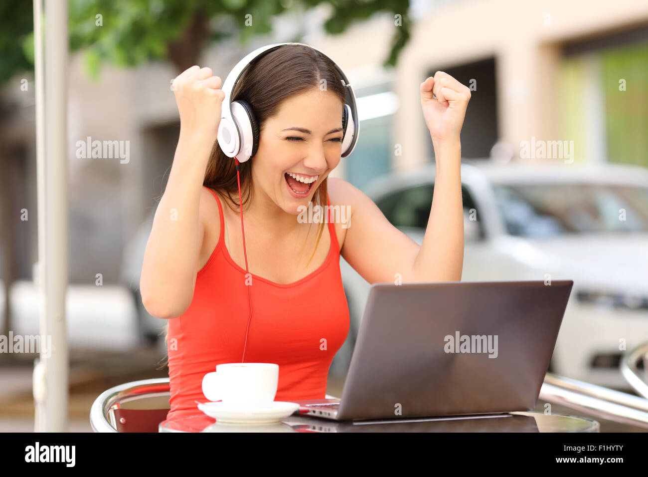 Gewinner Mädchen euphorisch beobachten einen Laptop in einem Café trägt ein rotes Hemd Stockfoto