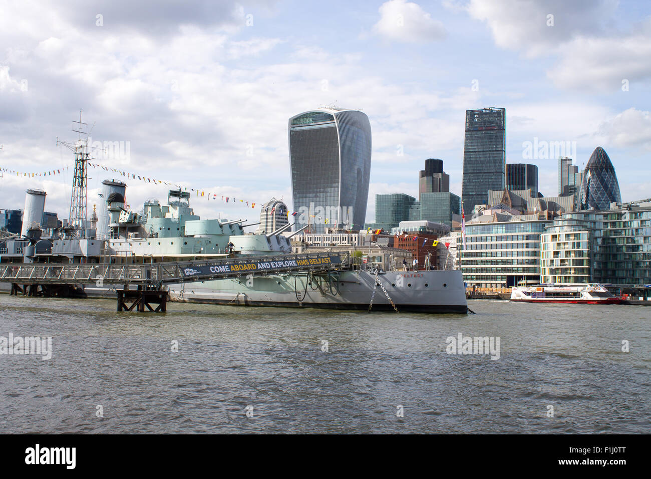 HMS Belfast, berühmte Kriegsschiff auf Themse. London City auf einem Hintergrund. Touristen auf dem Deck des Schiffes. Stockfoto