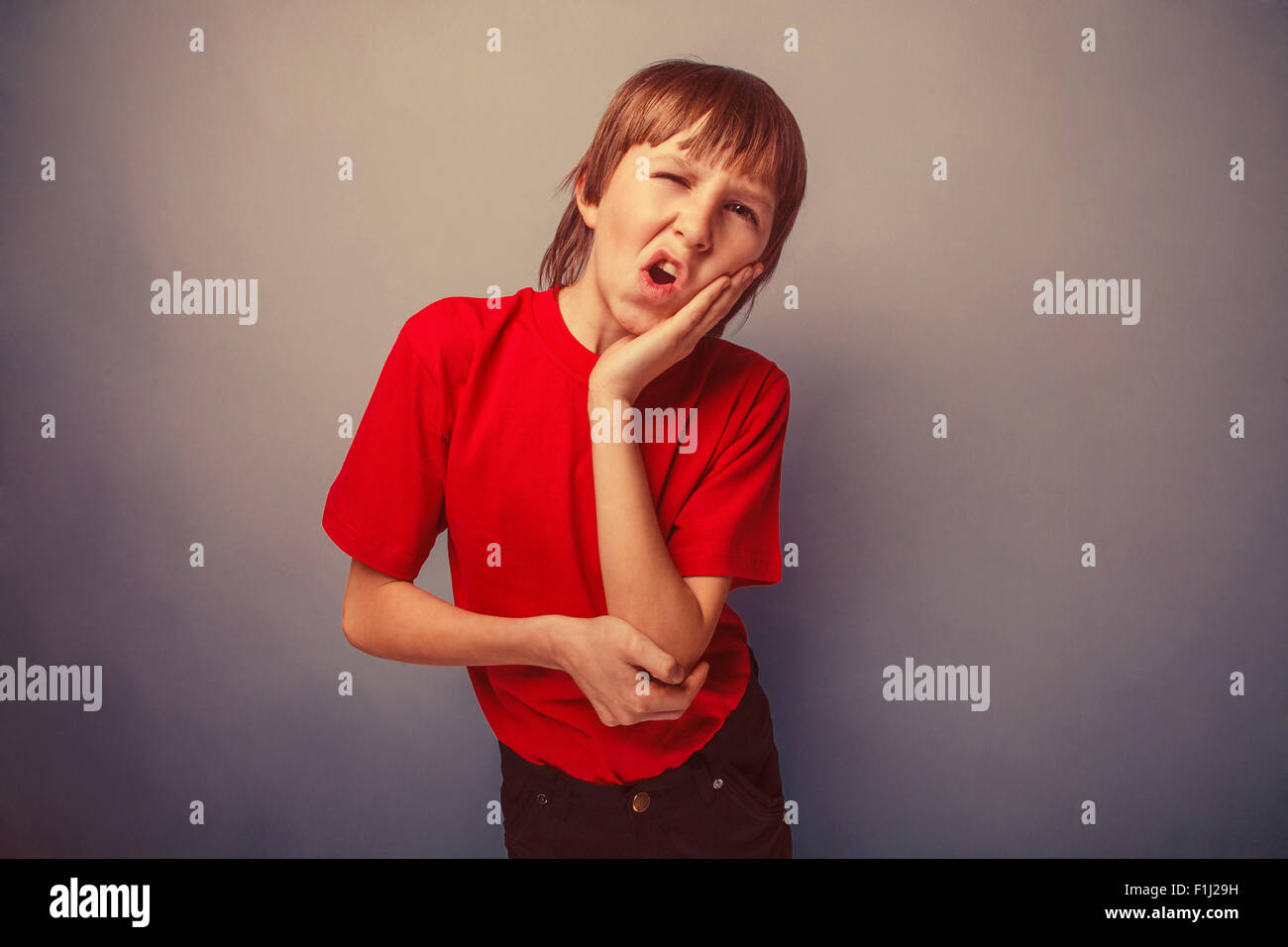 Junge, Jugendliche, zwölf Jahre im roten T-shirt Zahnschmerzen retro Stockfoto