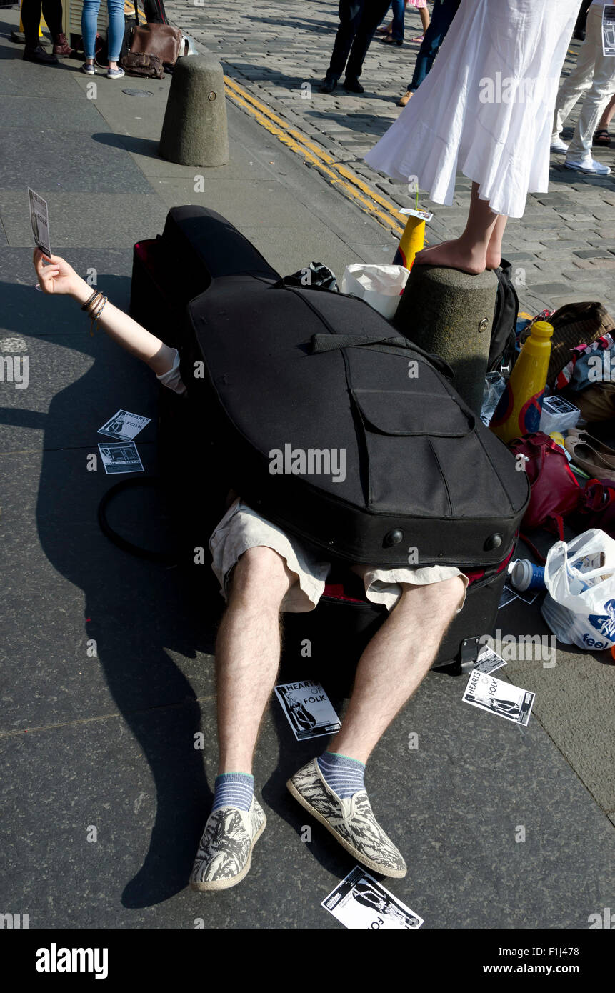 Mann in einem Cellokasten hält eine Broschüre zu seiner Show auf dem Edinburgh Festival Fringe in 2015 zu fördern. Stockfoto