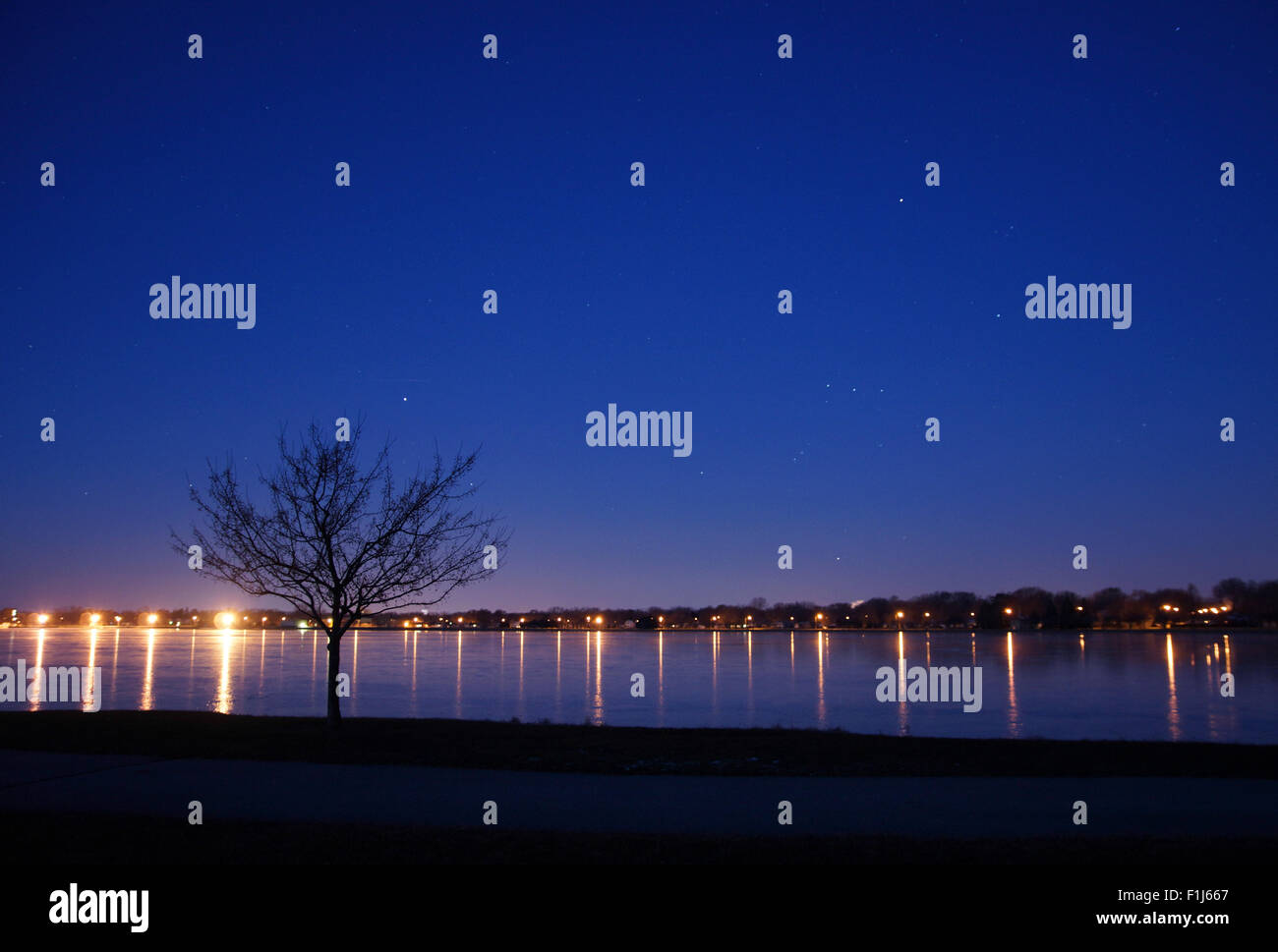 Der Nachthimmel verblasst Morgenlicht und Orion der Jäger beginnt zu sinken bis zum Horizont, unten die Lichter der Stadt und die gefrorenen l Stockfoto