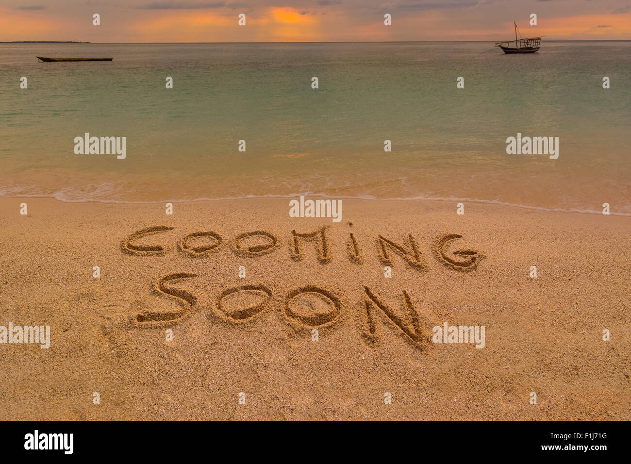 Auf dem Bild einen Strand bei Sonnenuntergang mit den Worten auf dem Sand "Cooming bald". Stockfoto