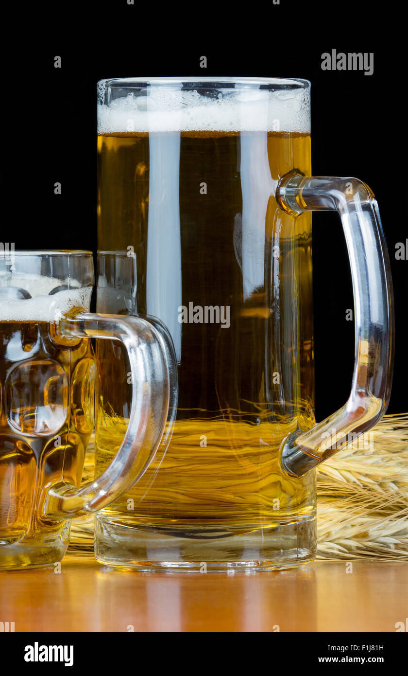 Pints Bier mit Weizen auf schwarzem Hintergrund. Stockfoto