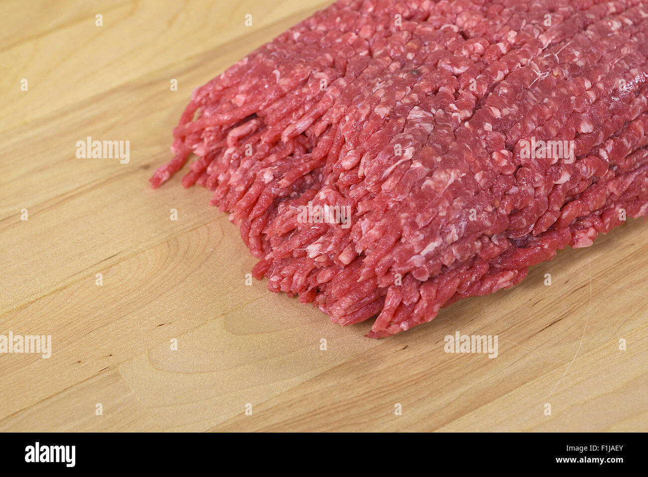 Rohes Rindfleisch Hamburger auf einem hölzernen Butcher-Block. Stockfoto