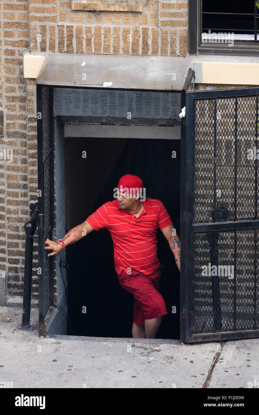 Hispanic Mitglied der Straßengang "Bloods" gekleidet in rot stehen heimlich in ein Zugangsstollen eines Mehrfamilienhauses. Stockfoto