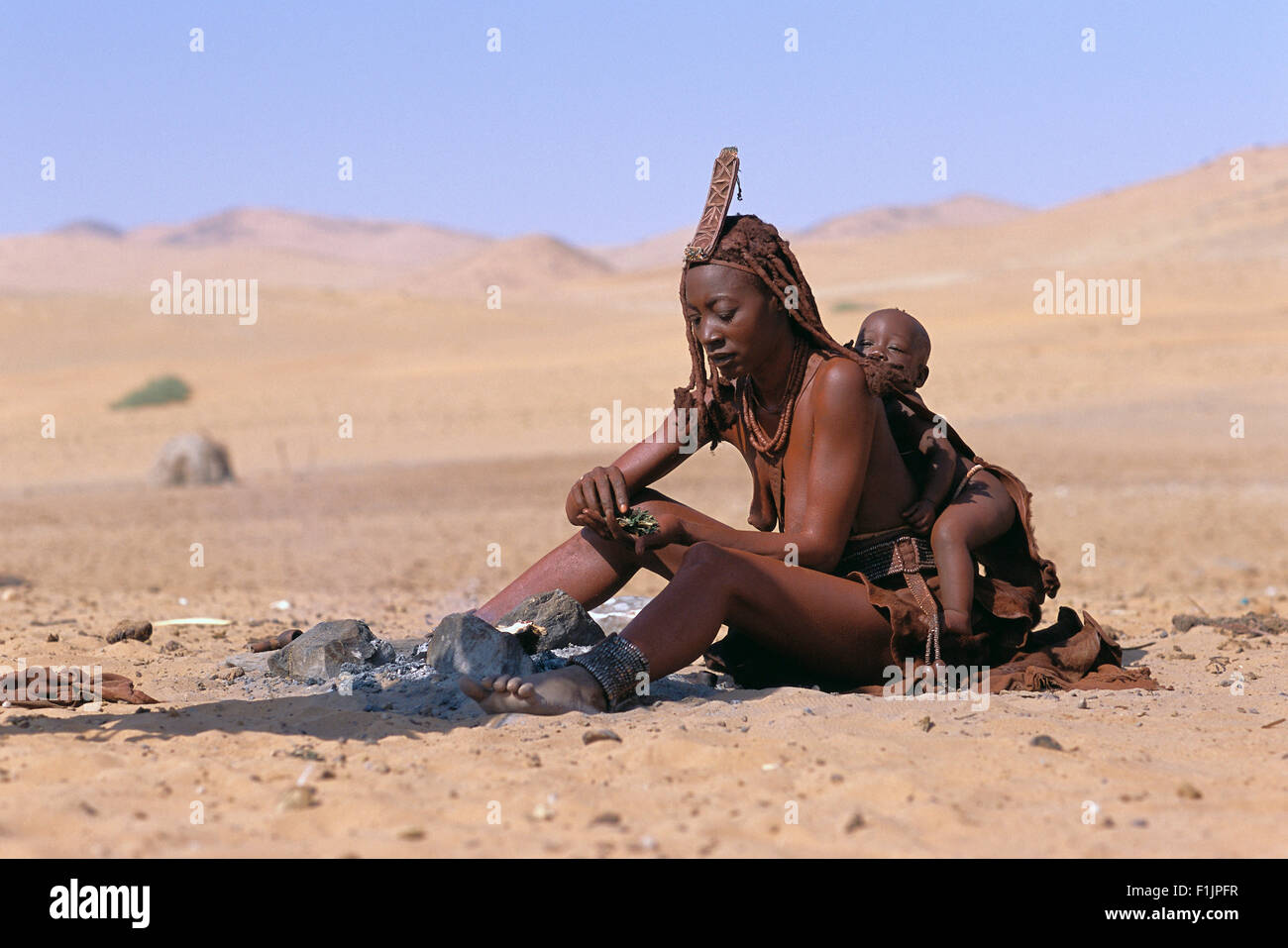 Himba Frau und Kind sitzt in der Nähe von Feuer, Namibia, Afrika Stockfoto