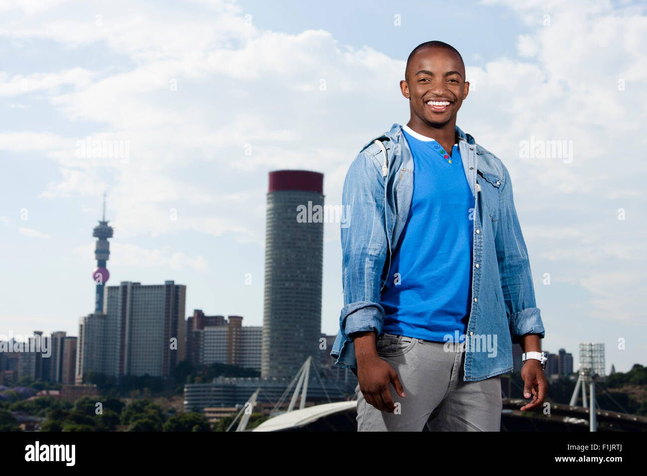 Lässig gekleidet junger schwarzer Mann steht vor Stadtbild Stockfoto