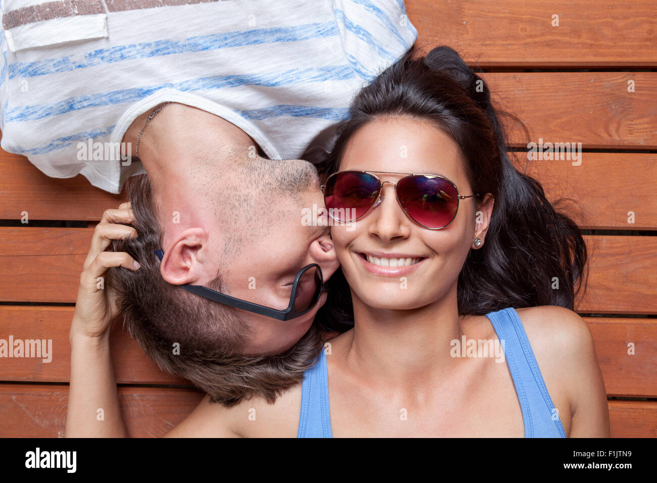 Glückliches junges Paar liegen Kopf an Kopf auf einem Holzfußboden Stockfoto