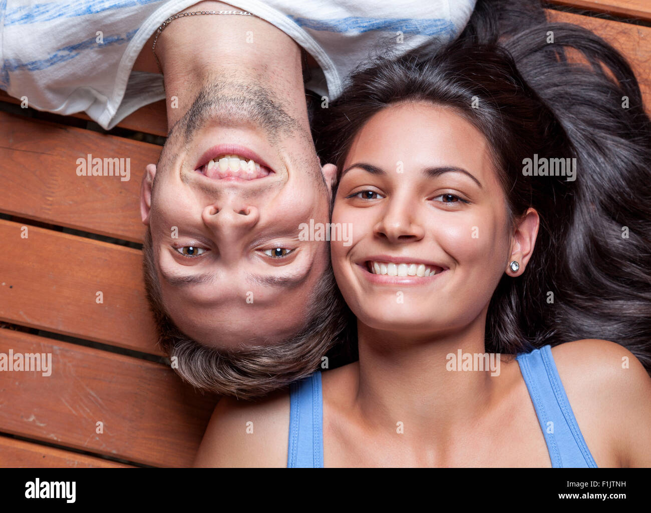 Glückliches junges Paar liegen Kopf an Kopf auf einem Holzfußboden Stockfoto