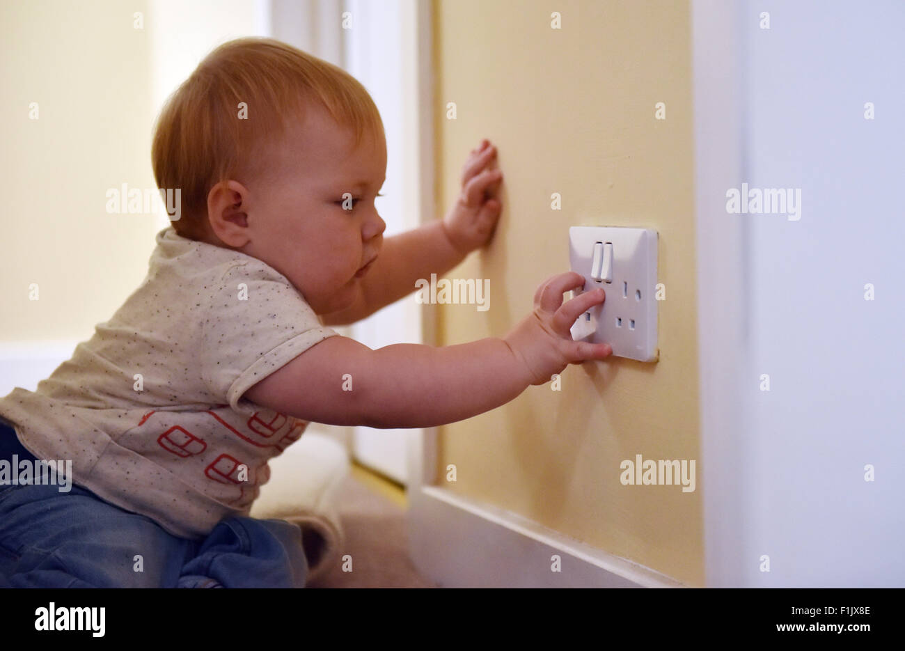 Ein elf Monate altes Baby mit einer elektrischen Steckdose in ihrem Haus zu spielen. Stockfoto